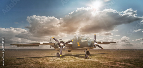 Canvas Print Old bomber in cloud of dust in the open field