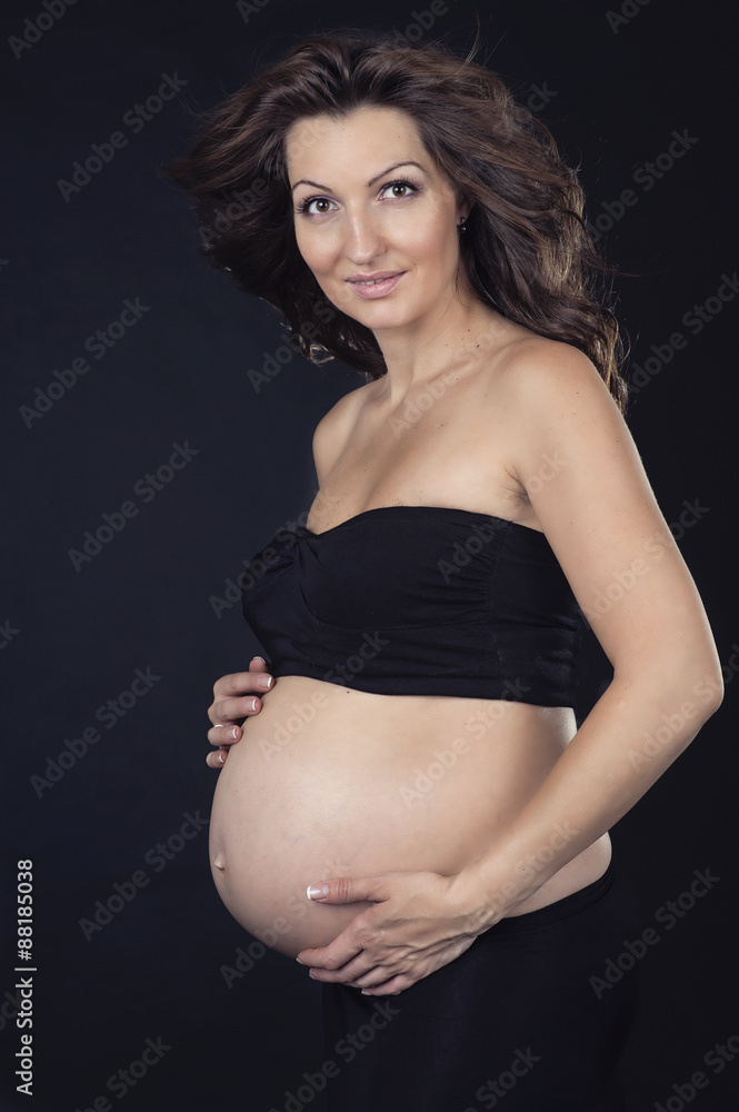 Pregnant woman on a black background in a studio Pregnant woman on a black background in a studio