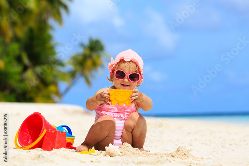 cute little girl playing with sand on the beach