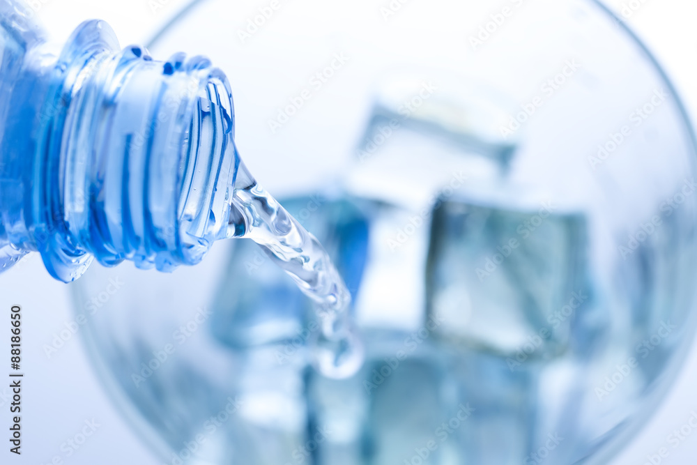 pouring water in an elegant glass with ice and water drops. Macro pouring water in an elegant glass with ice and water drops. Macro
