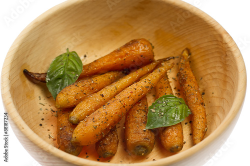 whole roasted carrots with spices in a wooden bowl on a white background. Vegetarian healthy food