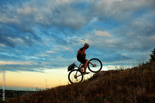 Silhouette of a biker and bicycle on sky background.