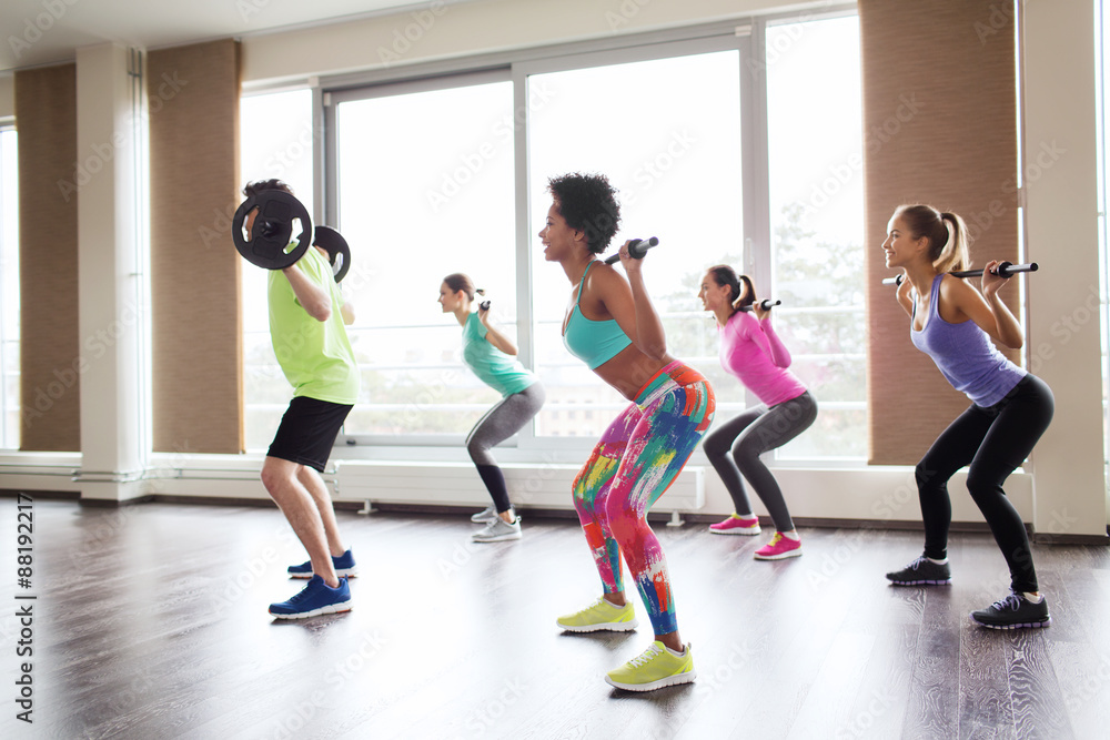 Naklejka premium group of people exercising with barbell in gym