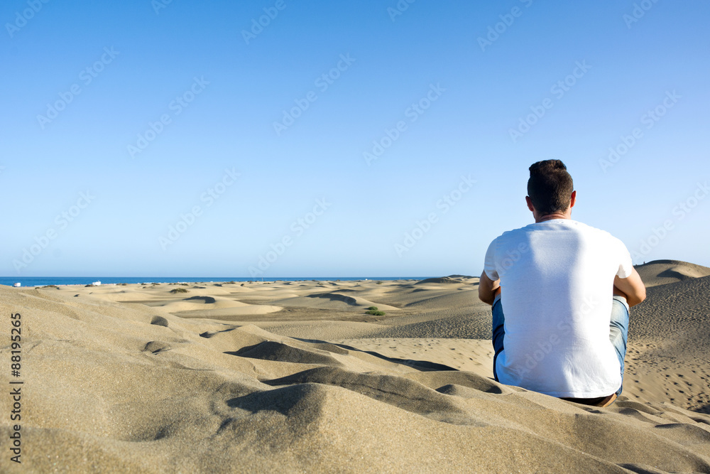 Young man sitting on a dune