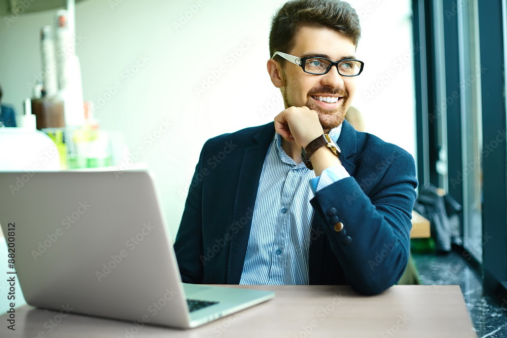 Young fashion smiling hipster man in the city cafe during lunch time with notebook in suit Young fashion smiling hipster man in the city cafe during lunch time with notebook in suit