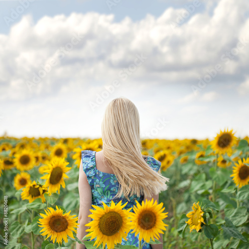 Portrait of a beautiful young blonde woman in blue dress on a ba