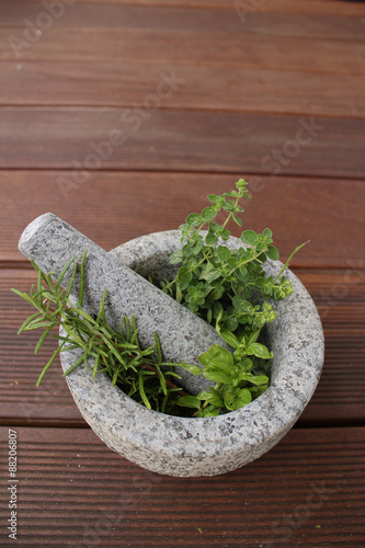 Healthy and fragrant herbs in a stone mortar photo