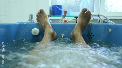 Man lies in the treatment bath in a spa, bath with oxygen and herbs
