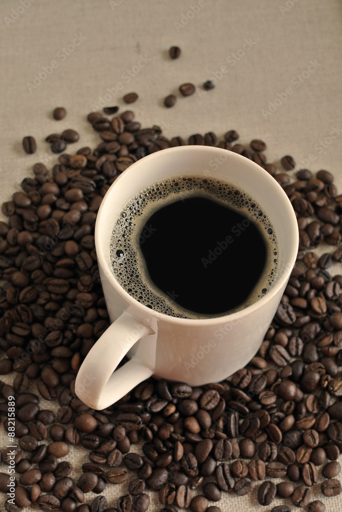 Naklejka premium White ceramic coffee mug with coffee beans on cloth sack