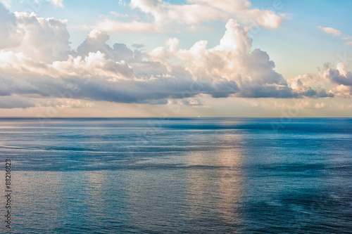 Elevated wide view of sea and blue sky with striking clouds at dawn. Background image, center horizon.