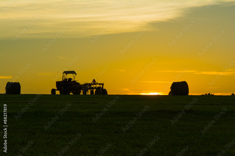Fototapeta premium Sunset with tractor and hay bales