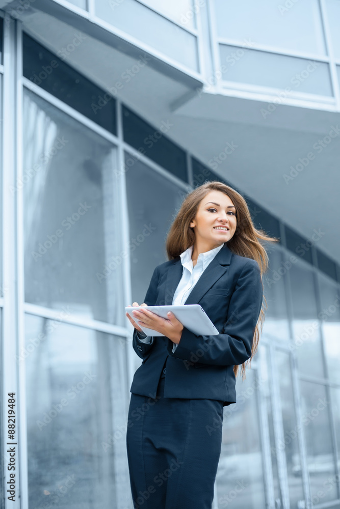Fototapeta premium Successful businesswoman or entrepreneur using a digital tablet computer, standing in front of his office.