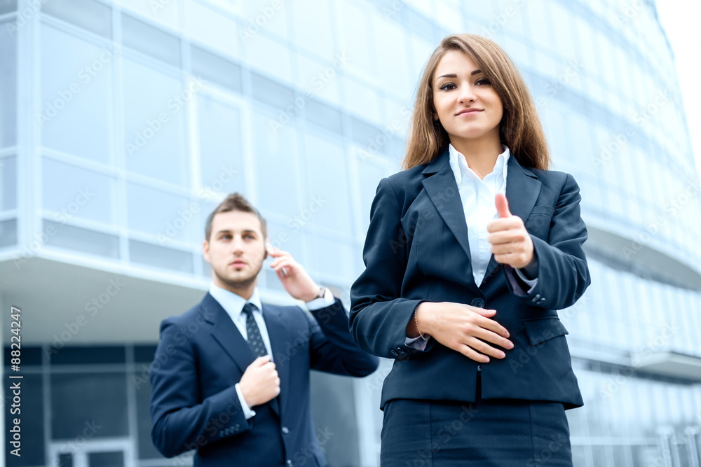 Successful young business woman showing thumbs up sign standing in front of his office. Successful young business woman showing thumbs up sign standing in front of his office.