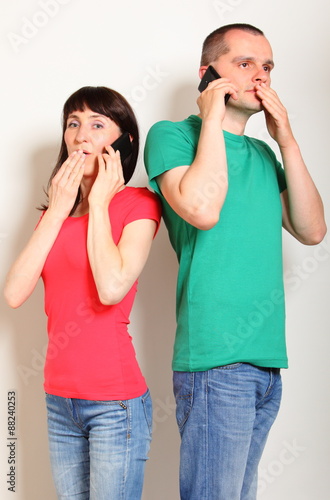 Shocked woman and man talking on mobile phone