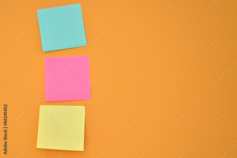 Three sticky note on a bright orange wall. Three sticky note on a bright orange wall.