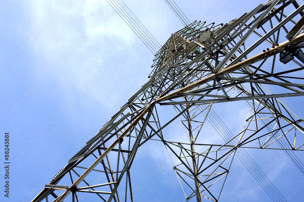 close-up low angle view of steel framework of high voltage tower pole with electricity transmission power lines and cloudy blue sky background, infrastructure domestic electric energy industry