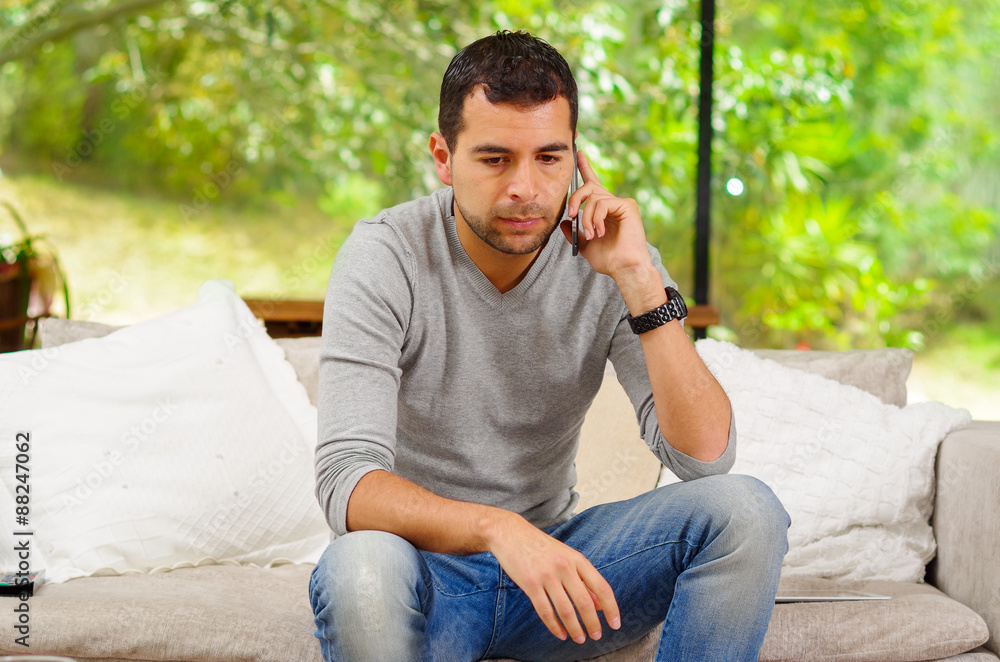 Hispanic man wearing denim jeans with grey sweater sitting in Hispanic man wearing denim jeans with grey sweater sitting in
