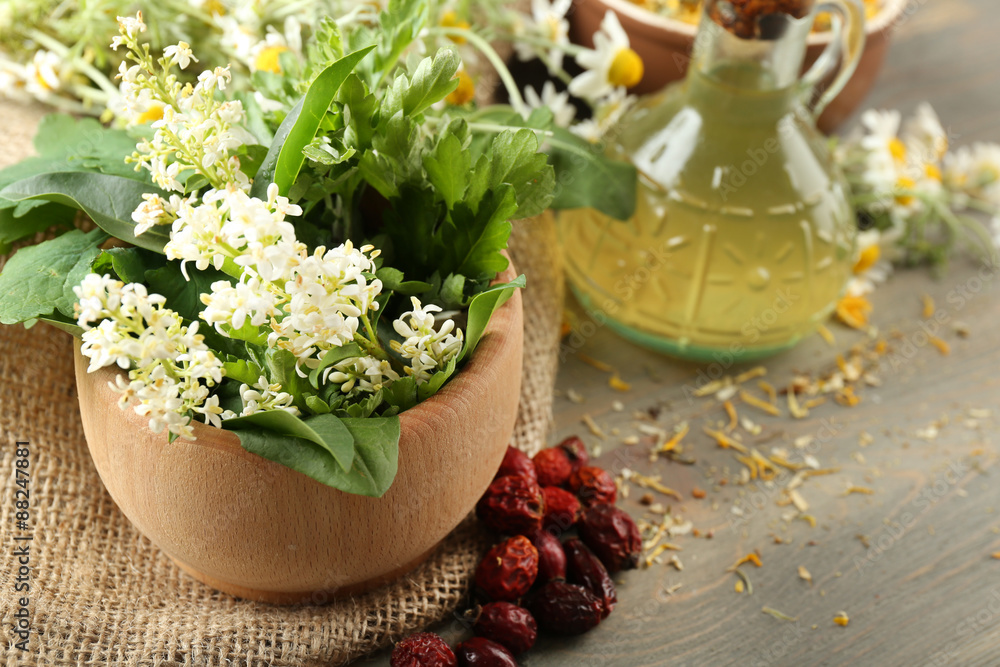 Herbs, berries and flowers with mortar, on wooden table background Herbs, berries and flowers with mortar, on wooden table background