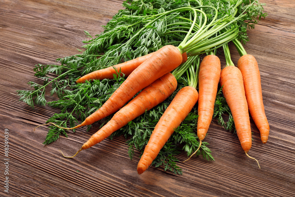 Fresh organic carrots with green tops on wooden background Fresh organic carrots with green tops on wooden background