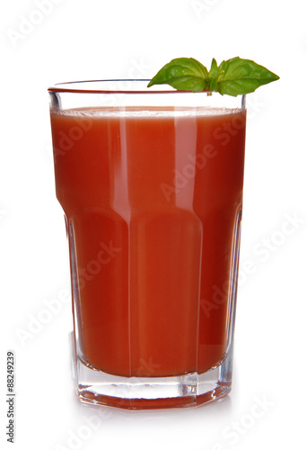 Glass of tomato juice with green leaves isolated on white