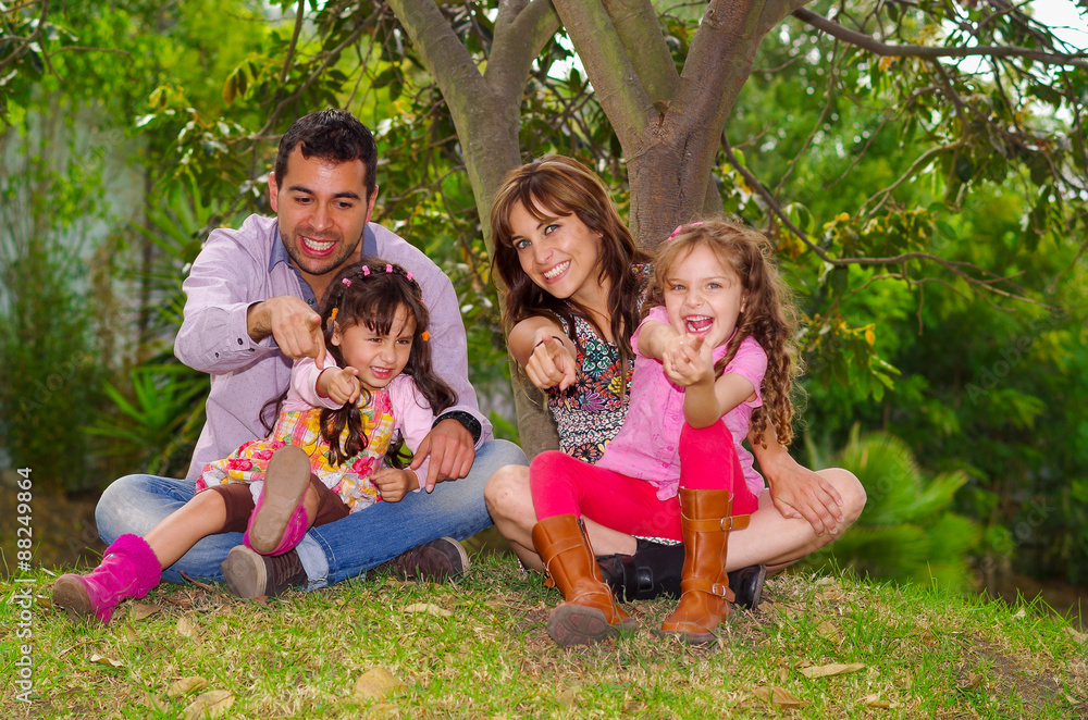 Family portrait of father, mother and two daughters sitting Family portrait of father, mother and two daughters sitting