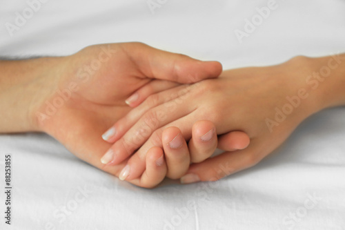 Male and female hands on white fabric background