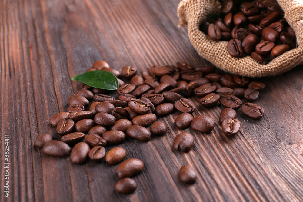 Coffee beans with leaf on wooden table close up Coffee beans with leaf on wooden table close up