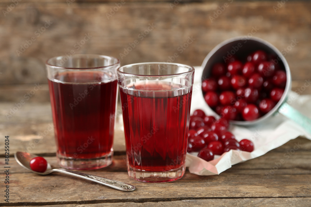 Two glasses with cherry juice on table, on wooden background Two glasses with cherry juice on table, on wooden background