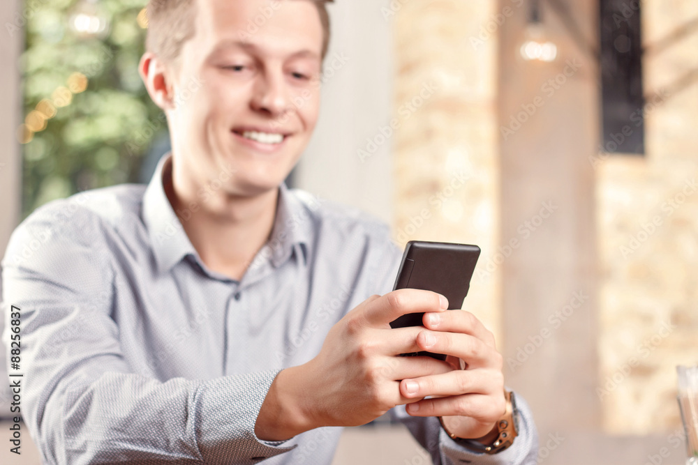 Handsome guy using mobile phone in cafe Handsome guy using mobile phone in cafe