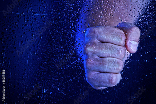 Male hand behind  wet glass  close-up