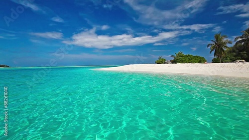 Palm trees over tropical lagoon with white beach in Maldives
