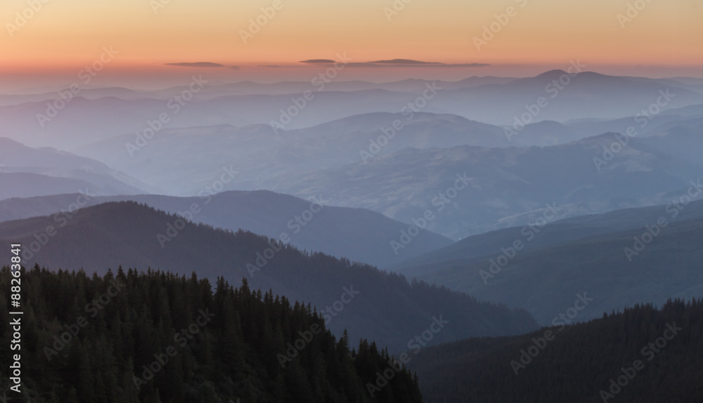 Distant mountain range and thin layer of clouds on the valleys