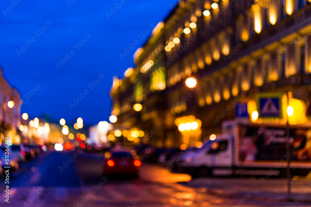 The bright lights of the evening city, the street going car. Defocused image