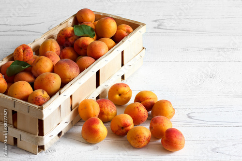Wood box of whole orange apricots with red blush on rustic white