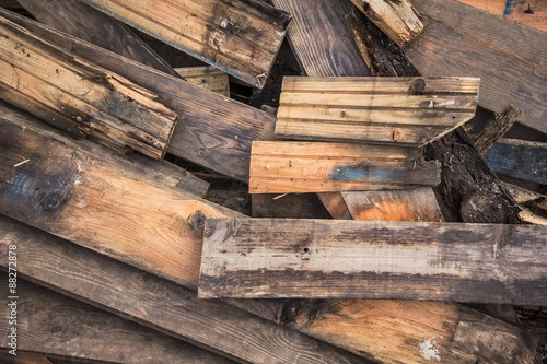 Photograph of old, rotten, scrapped floorboards and decking planks amassed and scattered in a untidy heap.