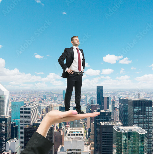 Woman's hand is holding a confident handsome businessman in a formal suit. New York city background.