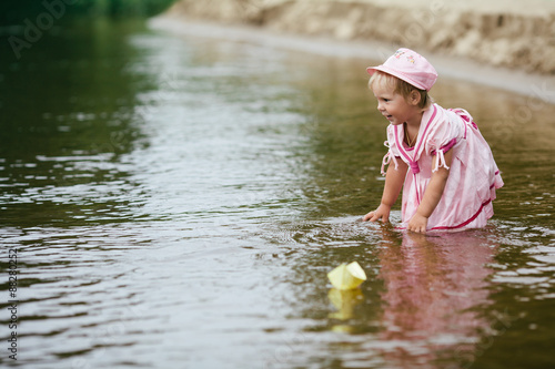 Fototapeta Naklejka Na Ścianę i Meble -  girl plays with paper boats in river
