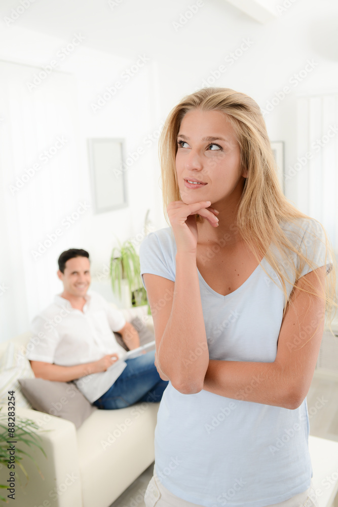 portrait of an attractive young woman at home with boyfriend in background portrait of an attractive young woman at home with boyfriend in background