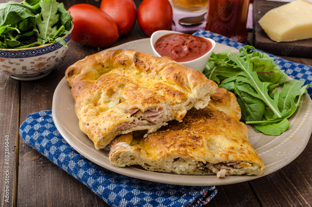 Calzone pizza stuffed with cheese and prosciutto