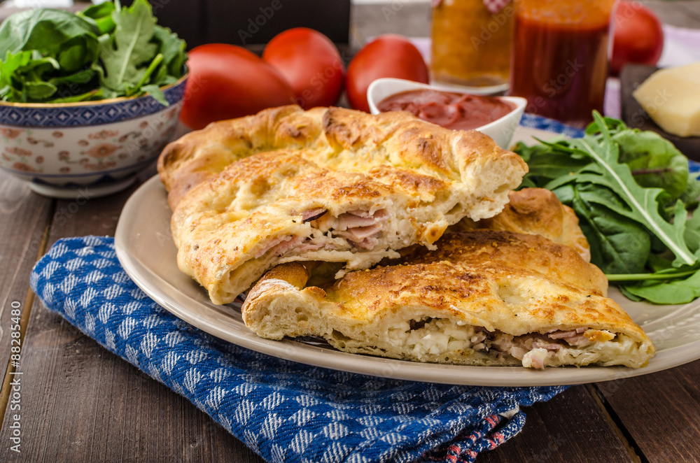 Calzone pizza stuffed with cheese and prosciutto Calzone pizza stuffed with cheese and prosciutto