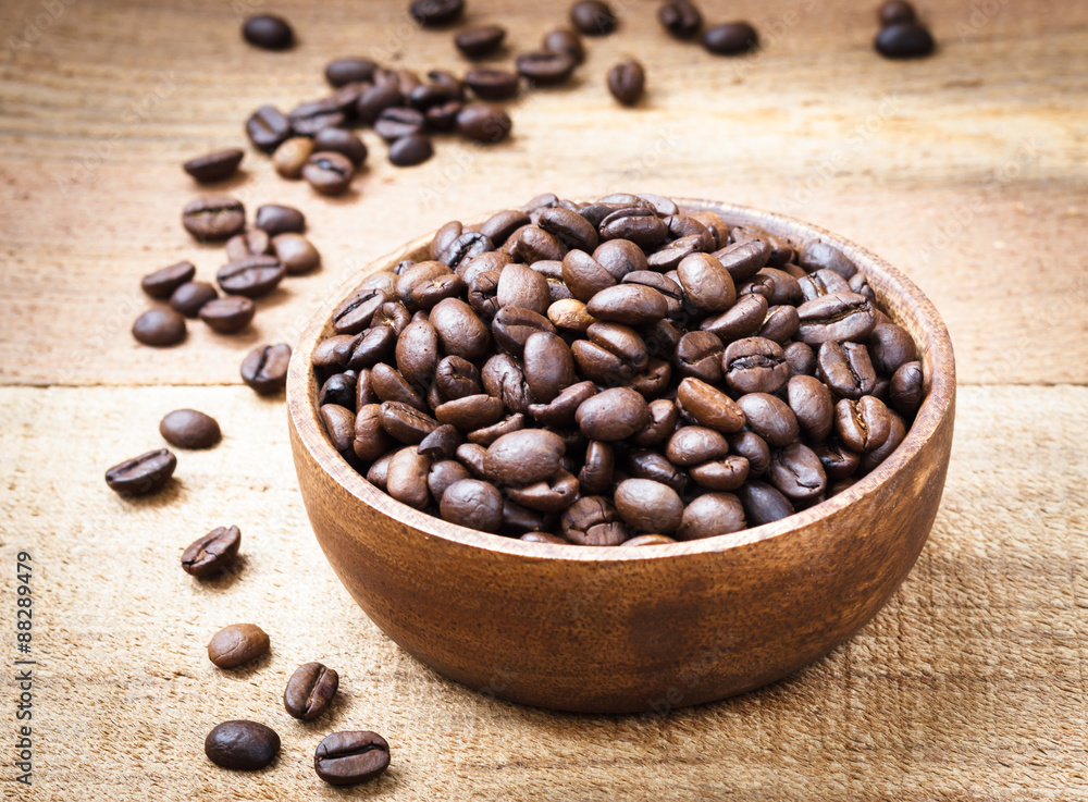 Coffee beans in wooden bowl on wooden background Coffee beans in wooden bowl on wooden background