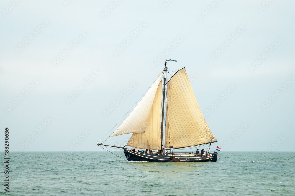 Traditional old Dutch wooden sailboat sailing on Waddensea, Netherlands