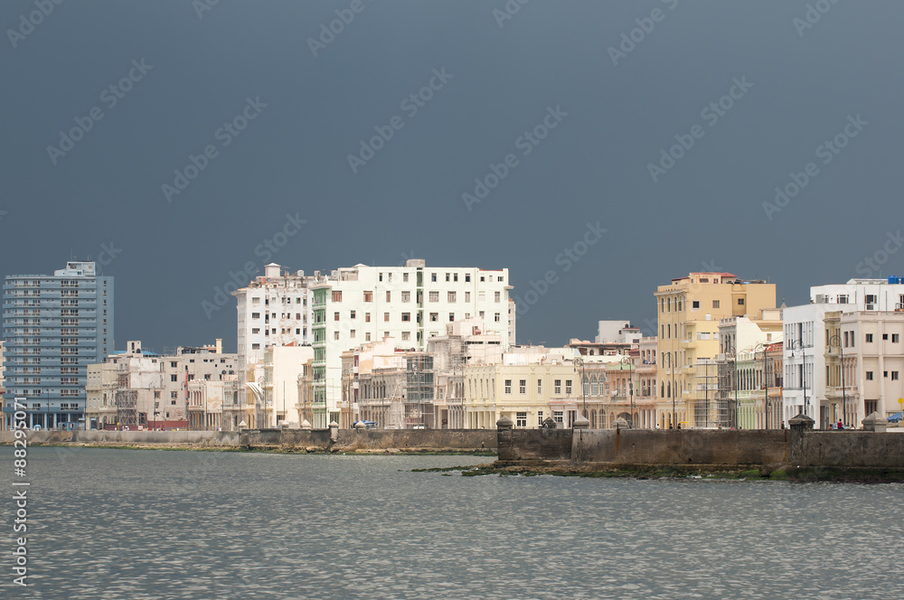 Dramatic dark sky contrasts with the pastel colors of the Malecon waterfront skyline in Havana, Cuba