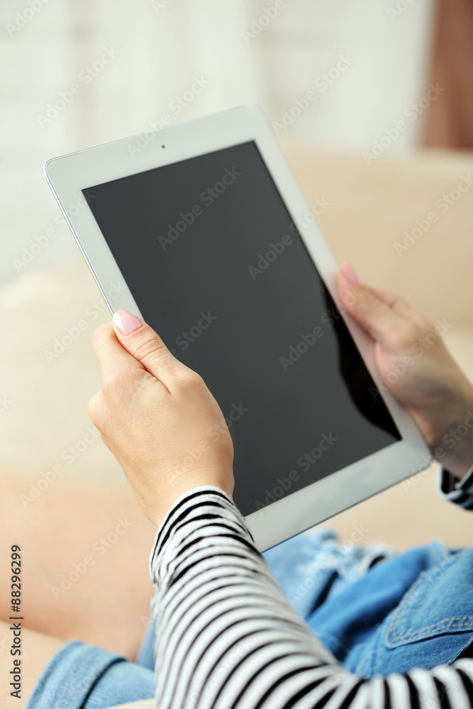 Female hand holding PC tablet on home interior background Female hand holding PC tablet on home interior background