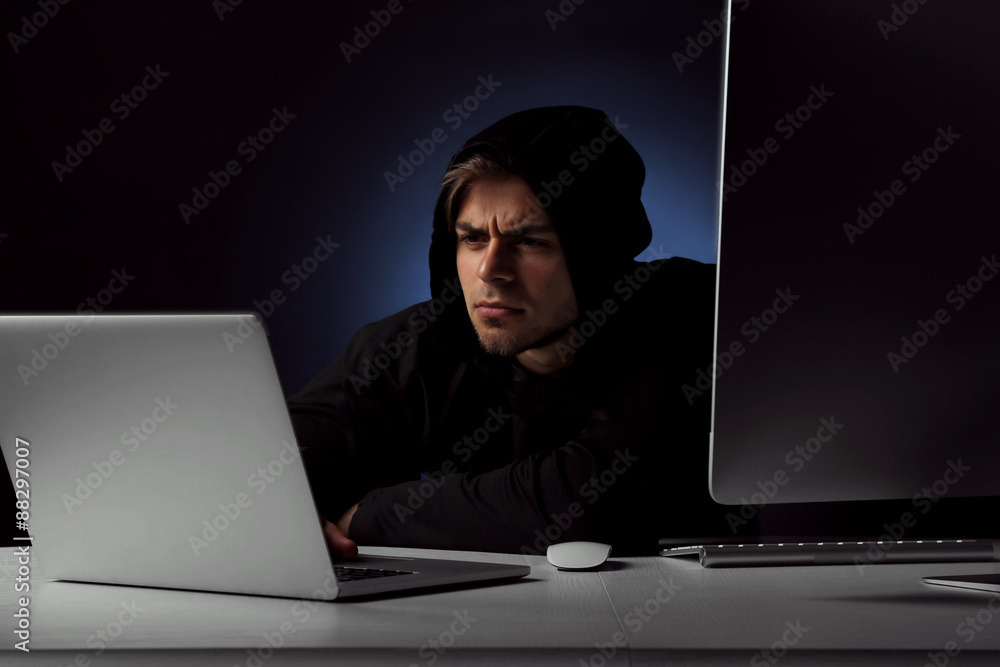 Hacker with computer and laptop on dark background Hacker with computer and laptop on dark background