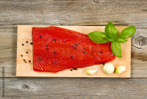 Fresh red salmon fillet on cedar cooking plank with spices and h photo