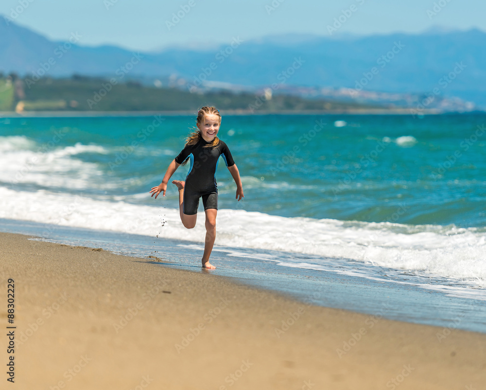 girl in a wetsuit running along the beach girl in a wetsuit running along the beach