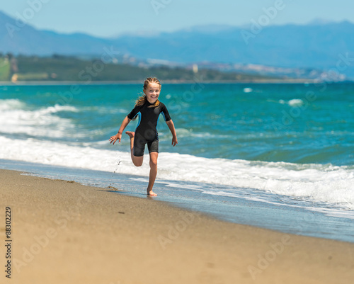 girl in a wetsuit running along the beach