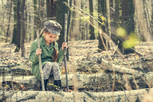 little girl in the woods sitting on a stump