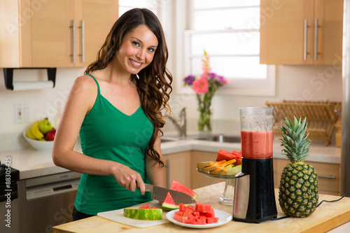 Portrait of a female beautiful young attractive cook chef brunette caucasian woman in kitchen healthy vegetarian vegan smoothie